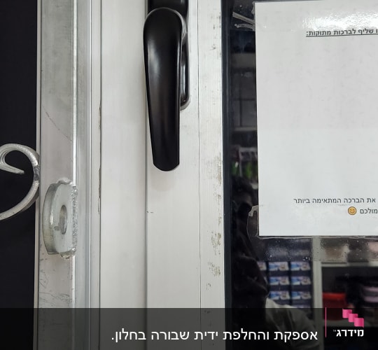 ידית תריס שחורה על מסגרת חלון לבנה